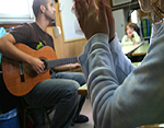 Profesor con alumnos tocando la guitarra y cantando