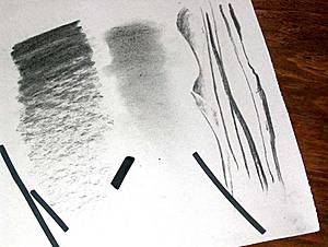 Fotografía de barras de carboncillo sobre un papel con distintos degradados, difuminados y líneas