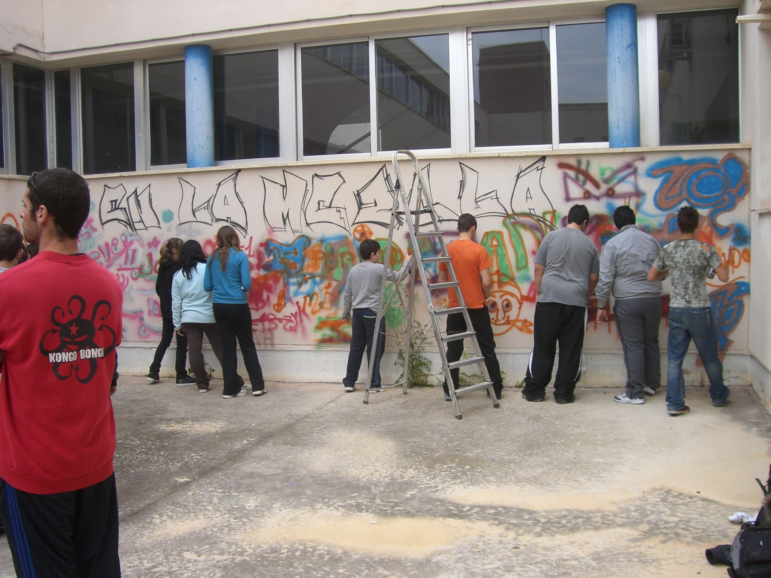 jóvenes pintando sobre el muro del instituto